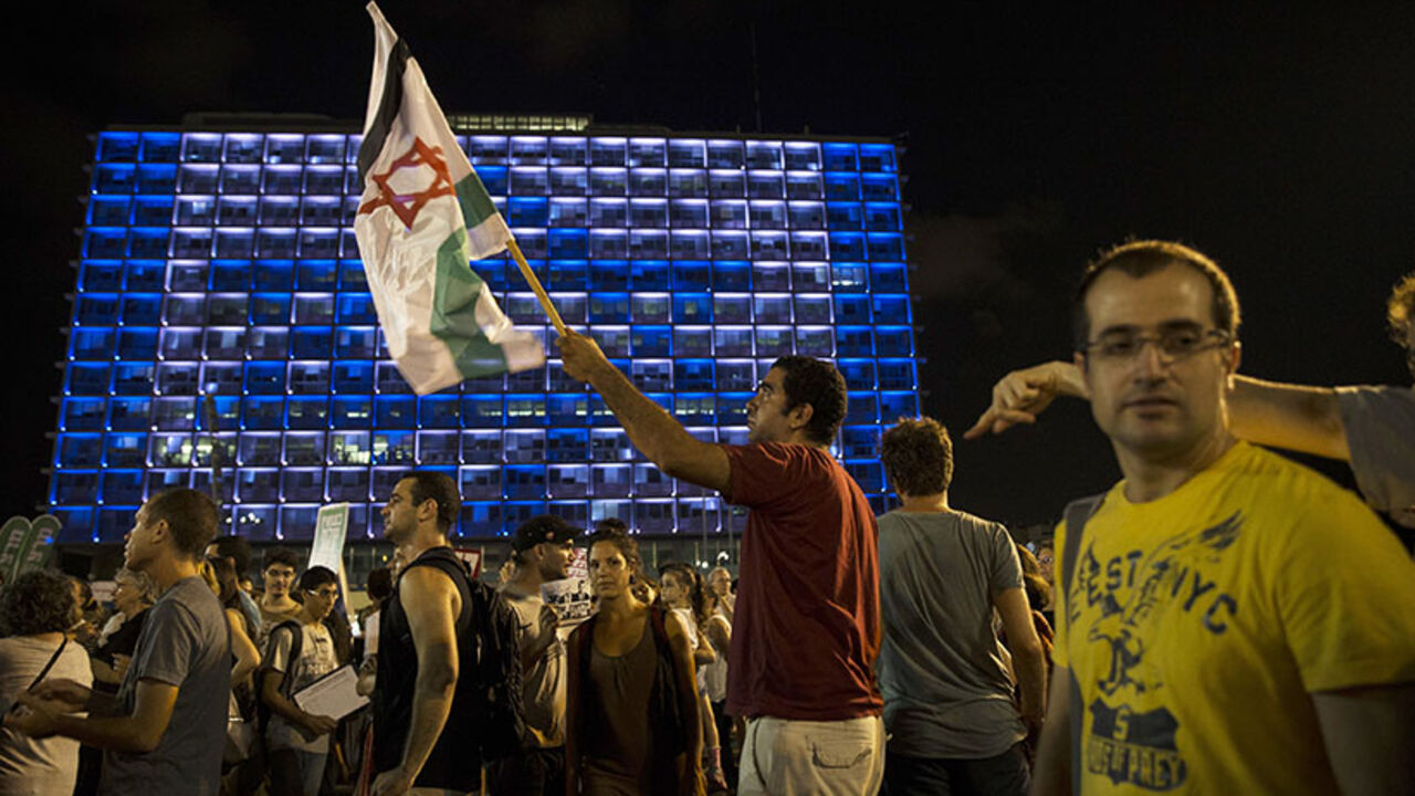 A man holds up a flag during a peace rally in Tel Aviv's Rabin Square August 16, 2014. The protesters were demonstrating in favour of a peaceful political agreement, to end the month-long conflict in Gaza, between the Israeli and Palestinian governments. 
REUTERS/Baz Ratner (ISRAEL - Tags: POLITICS CIVIL UNREST TPX IMAGES OF THE DAY) - RTR42O64