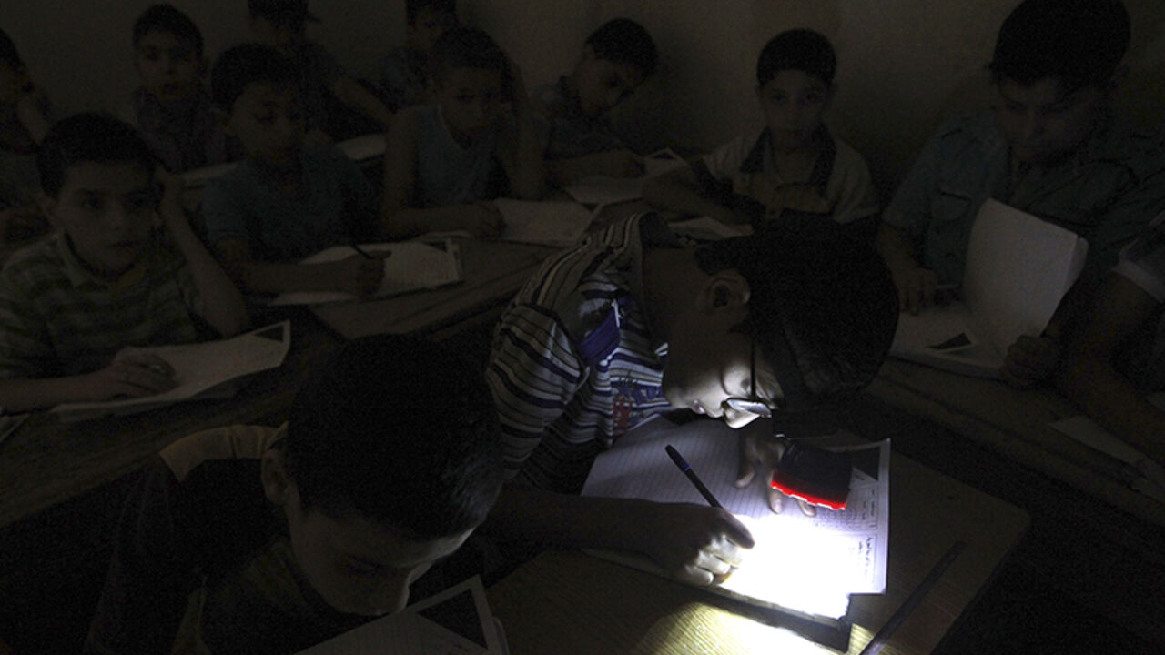 A student wears a headlight, due to electricity shortage, as he takes his year-end examinations at a school in Aleppo's al-Sha'ar district June 5, 2013. REUTERS/Muzaffar Salman (SYRIA - Tags: CONFLICT EDUCATION SOCIETY) - RTX10CK8
