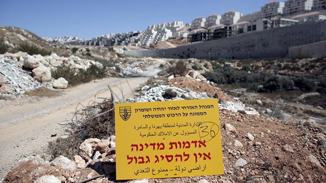 An official Israeli sign from the Civil Administration in Charge of the Government Property, placed in the West Bank near the Israeli Beitar Illit (R) settlement, states that the area is state land and trespassing is not allowed, near the Palestinian village of Wadi Fukin, on September 4, 2014. Israel over the weekend said it would expropriate 400 hectares (988 acres) of Palestinian land around Bethlehem, and allowed 45 days for any appeal. AFP PHOTO / AHMAD GHARABLI        (Photo credit should read AHMAD G