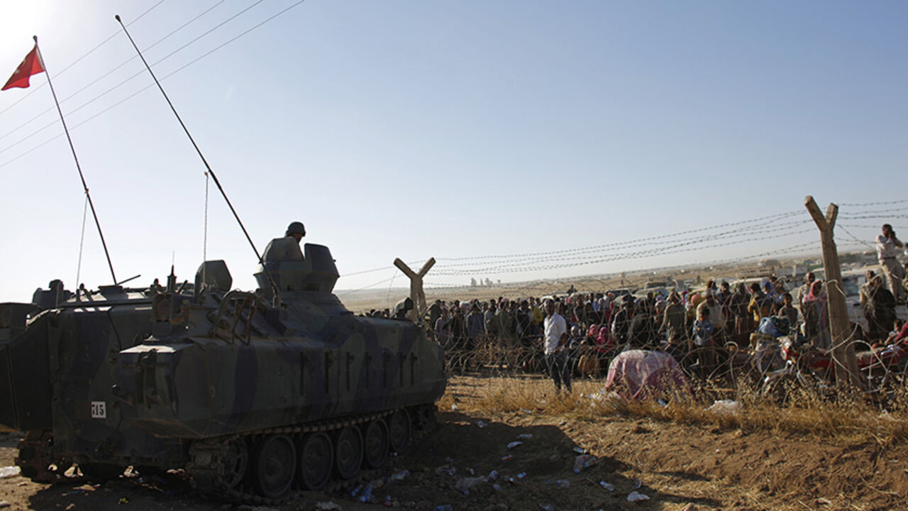 Turkish soldiers stand guard as Syrian Kurds wait behind the border fence near the southeastern town of Suruc in Sanliurfa province September 22, 2014. More than 130,000 Syrian Kurds fleeing an advance by Islamic State militants have crossed into Turkey in the past three days and the authorities are preparing for more, Turkish Deputy Prime Minister Numan Kurtulmus said on Monday.  REUTERS/Murad Sezer (TURKEY - Tags: POLITICS MILITARY CIVIL UNREST CONFLICT) - RTR476TU
