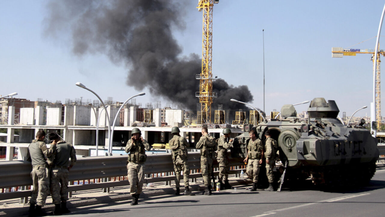 Turkish soldiers stand guard on a main street, as smoke rises in the background from burning tyres set alight by protesters, in Diyarbakir October 8, 2014. At least 12 people died on Tuesday during violent clashes across Turkey, local media reported, as the fate of the besieged Syrian border town of Kobani stirred up decades of tensions with Turkey's Kurdish minority. Violence erupted in Turkish towns and cities mainly in the Kurdish southeastern provinces, as protesters took to the streets to demand the go