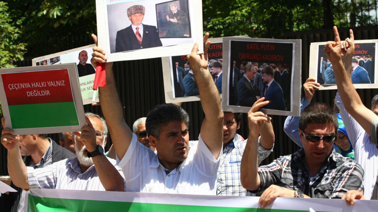 Protestors hold images of Medet Unlu, a Chechen activist based in Turkey who was killed on May 22 as they protest his death outside the Russian embassy in Ankara on May 25, 2013. 
AFP PHOTO/ADEM ALTAN        (Photo credit should read ADEM ALTAN/AFP/Getty Images)
