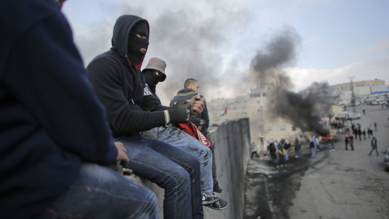 Palestinian protesters sit atop a section of Israel's controversial barrier that separates the West Bank town of Abu Dis from Jerusalem November 17, 2014. A Palestinian bus driver was found hanged inside his vehicle on Monday, an incident Israeli police described as a suicide but which the driver's family said they believed was an attack. Israeli police said the evidence suggested al-Ramouni had committed suicide, but rumors quickly spread in the Palestinian media that he had been killed by Jewish assailant