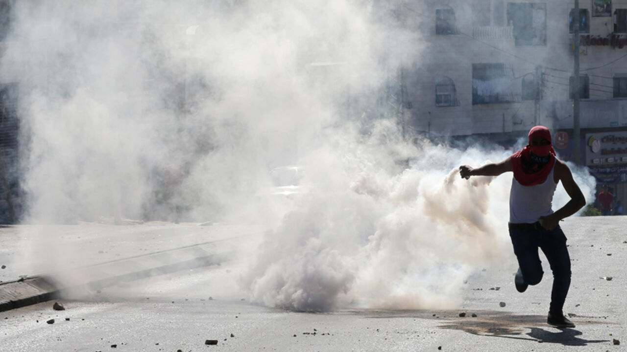 A Palestinian prepares to throw a tear gas canister fired by Israeli troops back to the soldiers during clashes following a gun battle where the troops shot dead two Palestinians, Marwan Kawasme and Amar Abu Aysha, in the West Bank city of Hebron September 23, 2014. Israeli troops shot dead the two Palestinians in the West Bank city of Hebron on Tuesday and the military said they were members of Hamas responsible for the killing of three Israeli youths in June, an attack that led to the Gaza war. Kawasme an