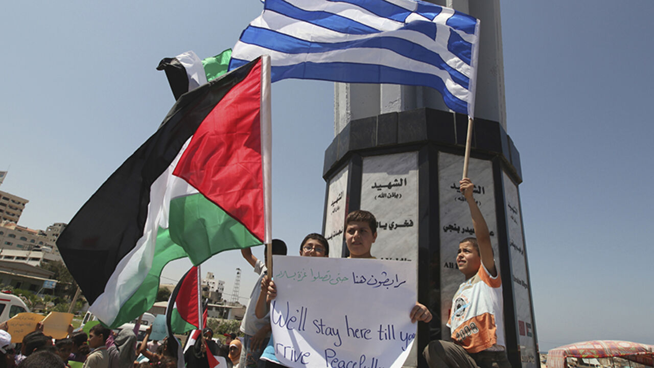 Palestinians hold flags during a rally in support of a Gaza-bound flotilla, at the Gaza seaport July 3, 2011. The pro-Palestinian flotilla hopes to leave Greece early this week to challenge Israel's sea blockade of the Gaza Strip, organisers said on Saturday. The convoy of cargo and passenger boats was due to depart at least a week ago but has been held up amid allegations of sabotage sponsored by Israel. REUTERS/Mohammed Salem (GAZA - Tags: POLITICS CIVIL UNREST) - RTR2OEST