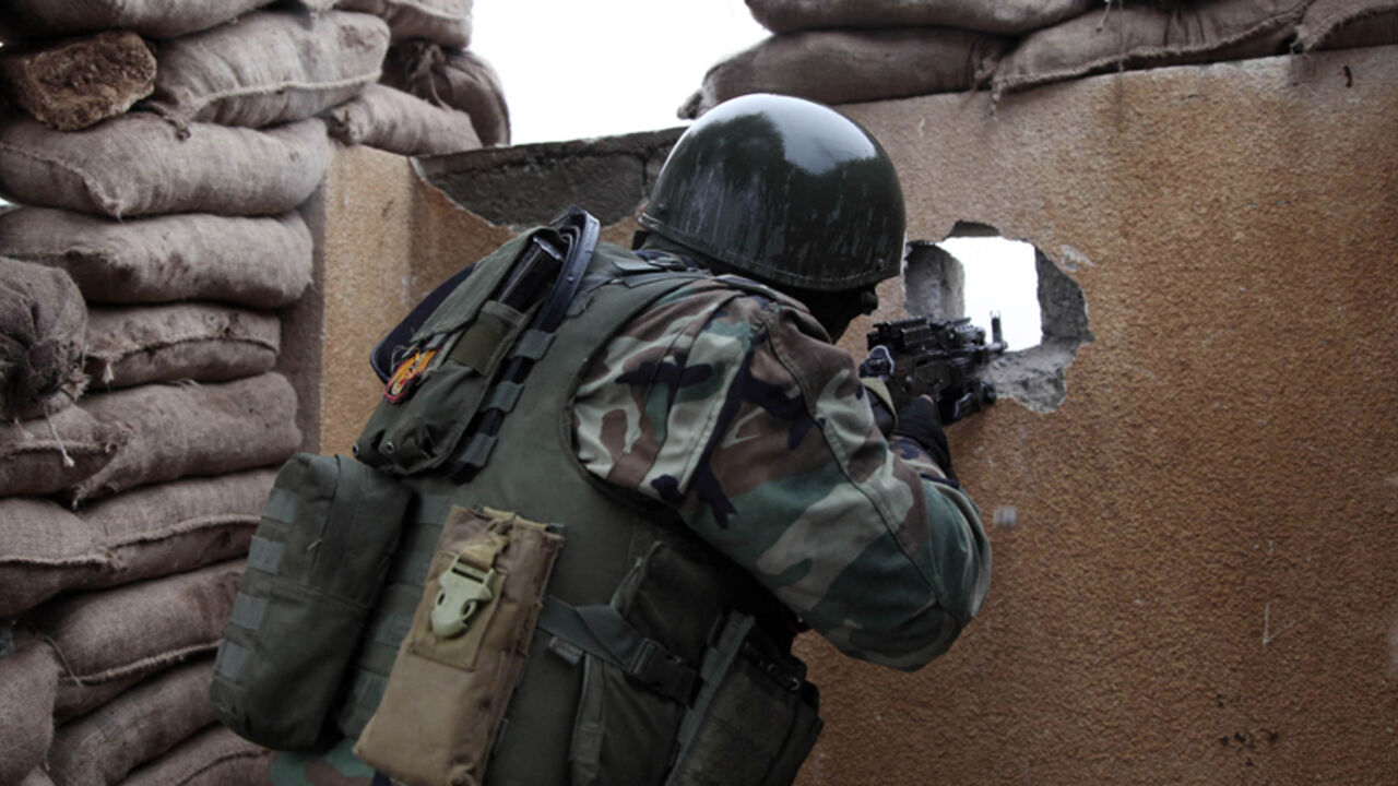 A Kurdish Peshmerga fighter aims his weapon through a hole in a wall on the front line of fighting against Islamic State militants in the outskirts of Mosul January 30, 2015.  REUTERS/Ari Jalal (IRAQ - Tags: CIVIL UNREST) - RTR4NNTG