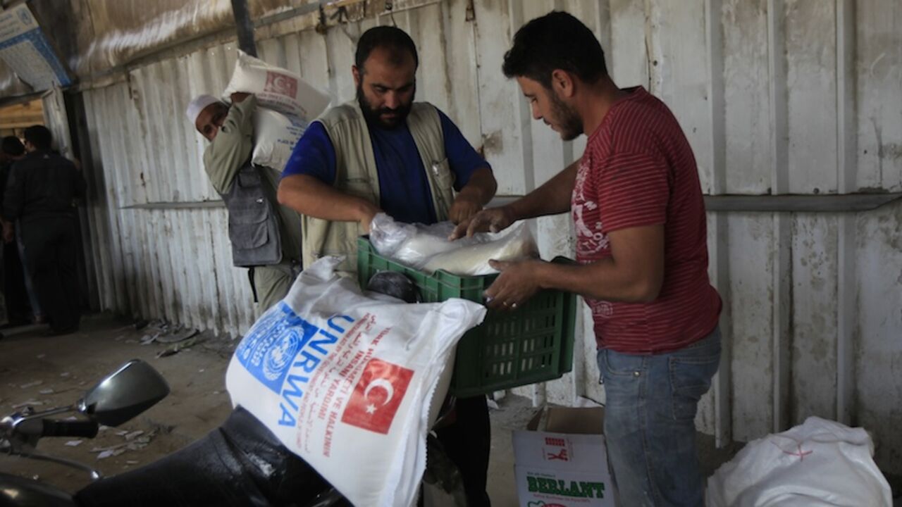 Palestinians collect food supplies from the United Nations Relief and Works Agency (UNRWA) headquarters in Rafah in the southern Gaza Strip on November 20, 2012. A group of 38 aid agencies urged the international community to take action to secure a ceasefire in Gaza to prevent "another widespread humanitarian disaster." AFP PHOTO/ SAID KHATIB        (Photo credit should read SAID KHATIB/AFP/Getty Images)