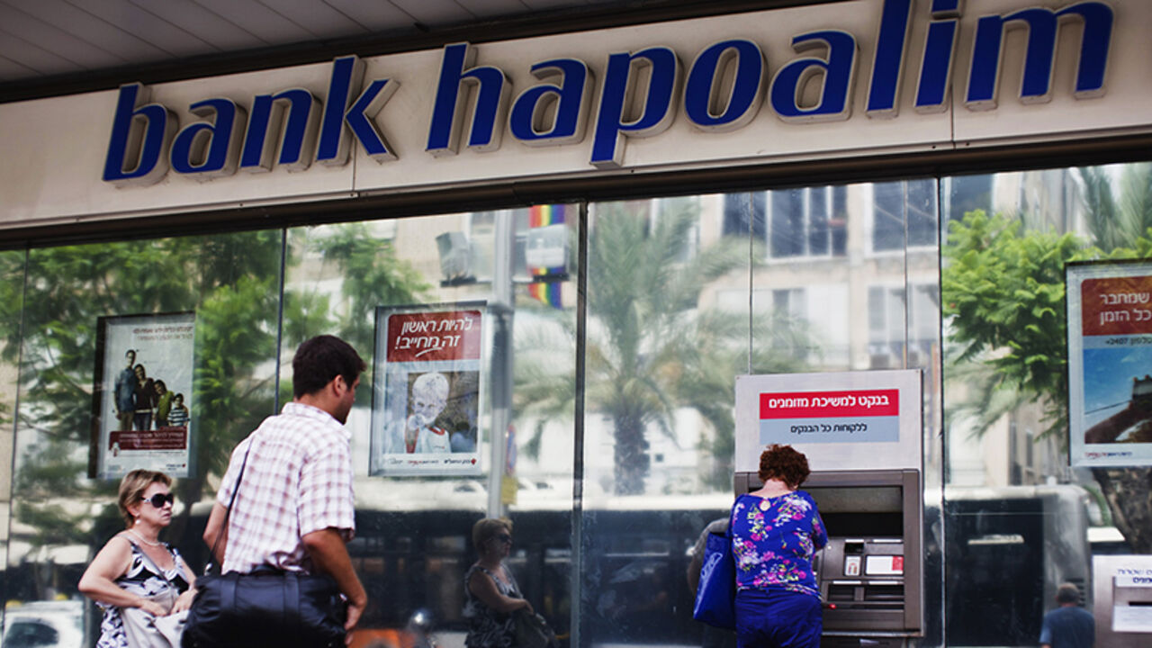 A woman uses an automated teller machine (ATM) outside a Bank Hapoalim branch in Tel Aviv May 30, 2013. Tough economic conditions and low interest rates hurt first-quarter profits at Israel's top two banks Hapoalim and Leumi, and two surprise rate cuts in May are expected to have a further impact in the coming quarters. REUTERS/Nir Elias (ISRAEL - Tags: BUSINESS) - RTX1061J