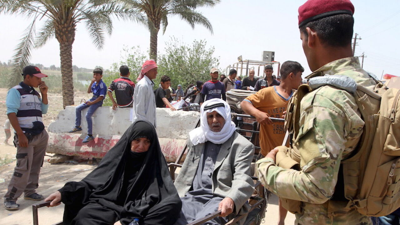 A member of the Iraqi security forces stands guard as displaced Sunni people, who fled the violence in the city of Ramadi, arrive at the outskirts of Baghdad, April 18, 2015. Iraqi security forces fought Islamic State militants at the gates of the western city of Ramadi on Friday, and local authorities warned it was in danger of falling unless reinforcements arrived soon.  REUTERS/Stringer - RTR4XVJ3