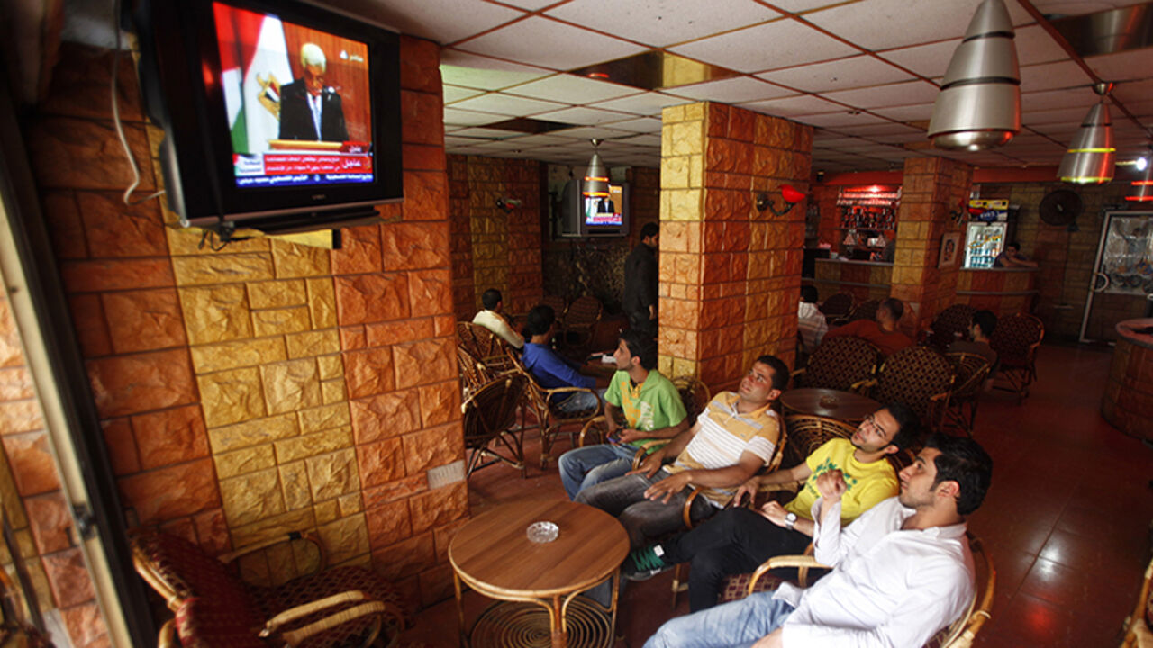 Palestinians watch the signing ceremony of the reconciliation agreement between rival Palestinian factions Fatah and Hamas, at a coffee shop in Gaza City May 4, 2011. President Mahmoud Abbas said on Wednesday Palestinians were turning a "black page" on division at the ceremony in Egypt to heal a four-year rift between his Fatah movement and Islamist group Hamas. REUTERS/Suhaib Salem (GAZA - Tags: POLITICS) - RTR2LZ9F
