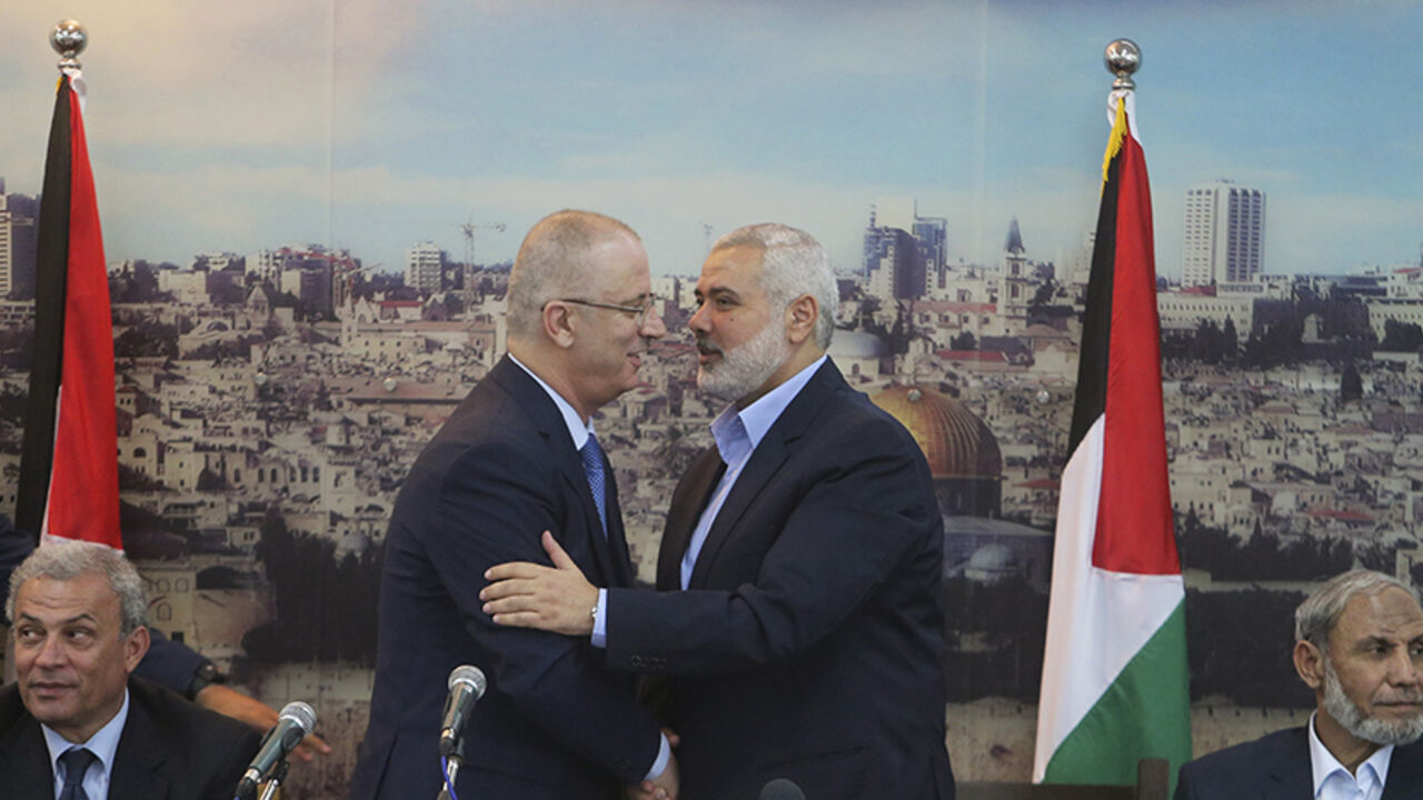 Senior Hamas leader Ismail Haniyeh (R) shakes hands with Palestinian Prime Minister Rami Hamdallah at Haniyeh's house in Gaza City October 9, 2014. Hamdallah arrived in the Hamas-dominated Gaza Strip on Thursday and convened the first meeting of a unity government there since a brief civil war in 2007 between Hamas and forces loyal to the Fatah party.    REUTERS/Ibraheem Abu Mustafa (GAZA - Tags: POLITICS CIVIL UNREST) - RTR49J7M