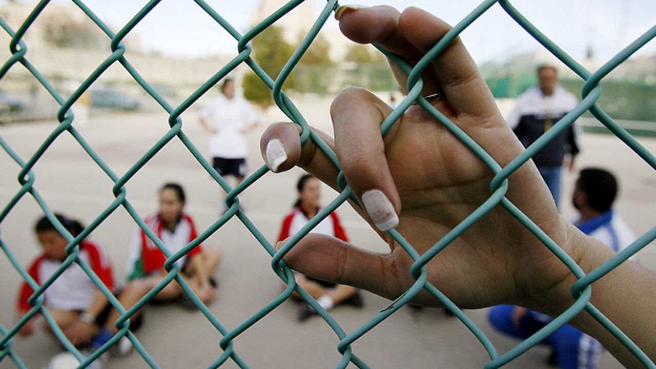A member of the Palestinian national women's soccer team leans on a fence during a training session in the West Bank town of Bethlehem February 20, 2007. Some 18 Palestinian athletes make up the women's national team that was founded in 2003 and joined FIFA in the summer of 2006. Picture taken February 20, 2007.   REUTERS/Eliana Aponte (WEST BANK) - RTR1MNTR