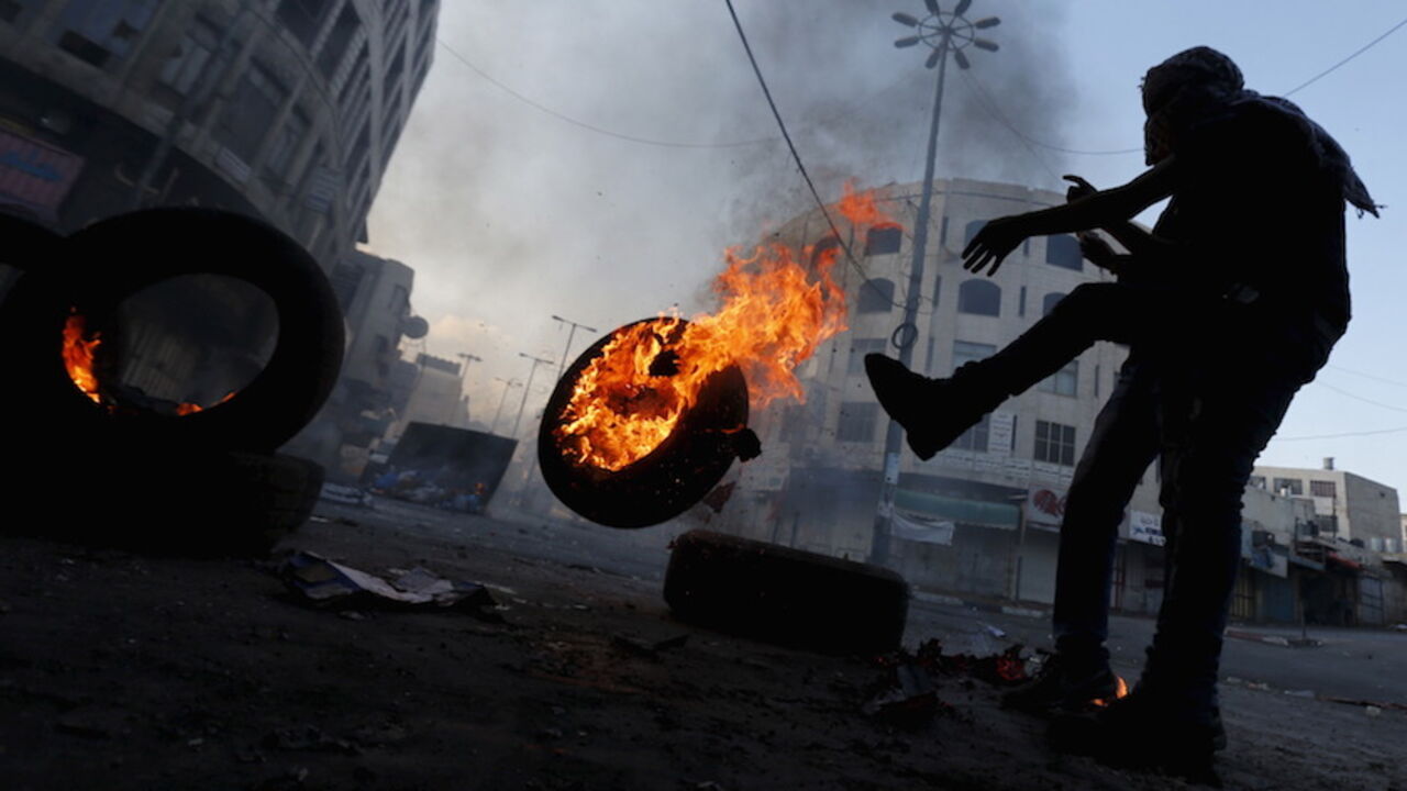 A Palestinian protester pushes a burning tyre during clashes with Israeli troops in the West Bank city of Hebron October 31, 2015. Israeli security forces shot and killed a Palestinian who ran at them with a knife in the occupied West Bank on Saturday, police said, as a month-long wave of violence showed no signs of abating. REUTERS/Ammar Awad - RTX1U4BU