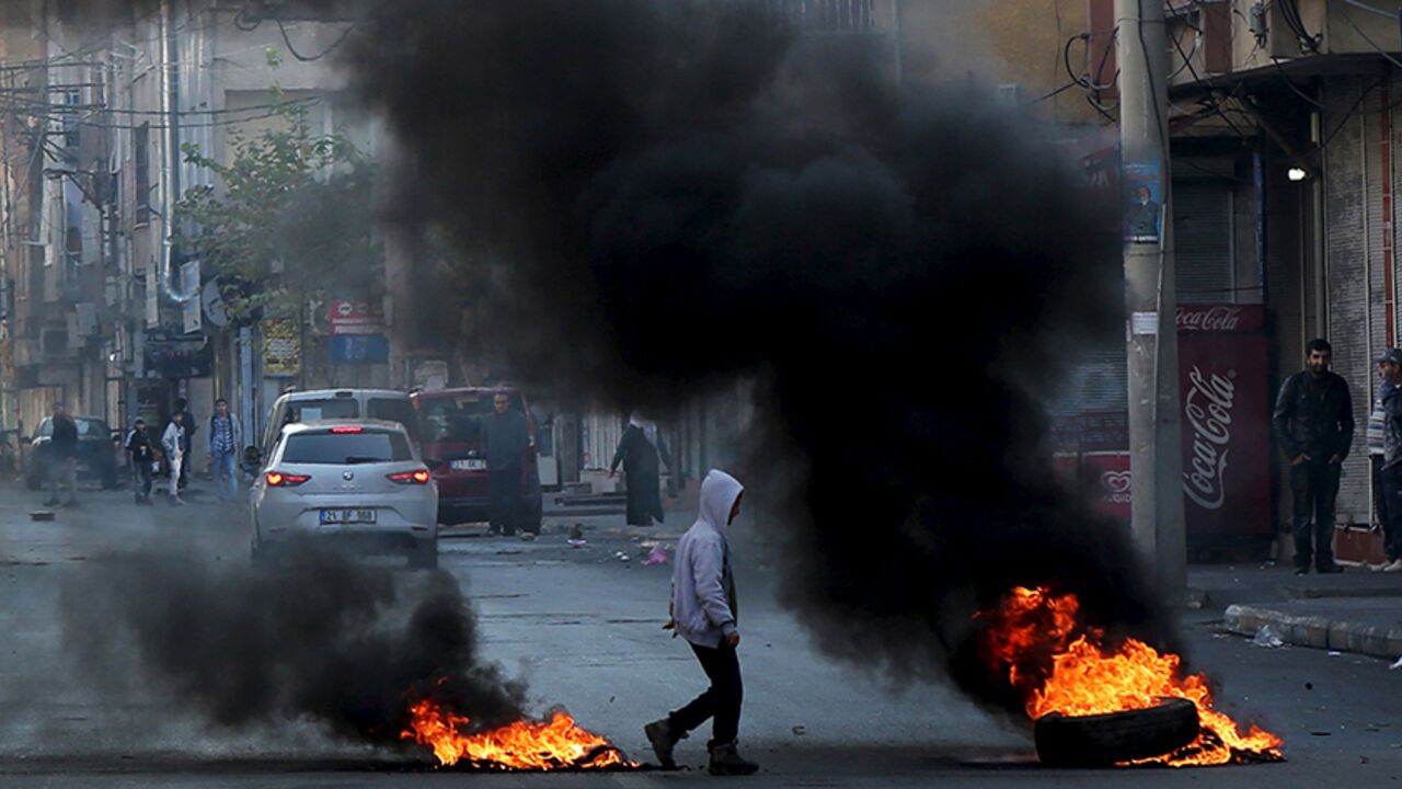 A boy walks past by burning tires during a protest against the curfew in Sur district, in the southeastern city of Diyarbakir, Turkey, December 14, 2015. REUTERS/Sertac Kayar - RTX1YNAN