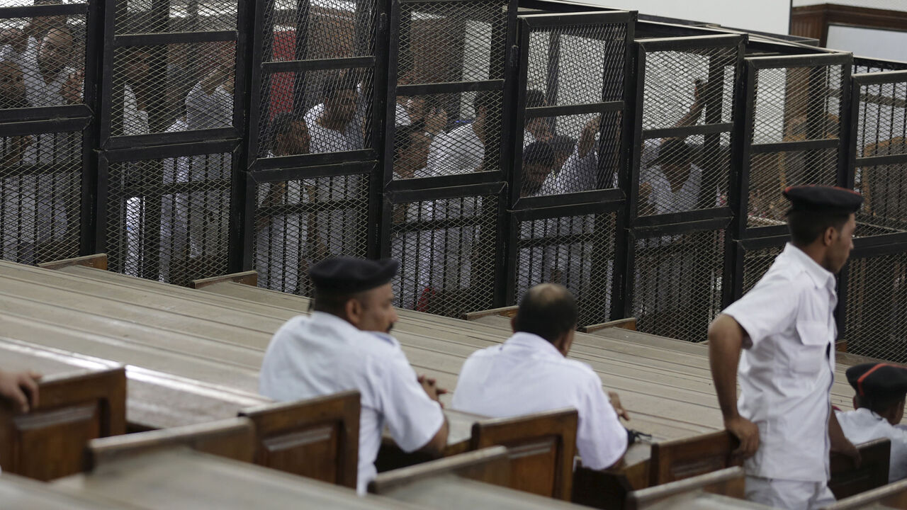 Suhayb Saad, an activist who rights groups say was taken by security forces and forced to confess on TV his membership of a terrorist cell, a reference to the Muslim Brotherhood, stands behind bars with other co-defendants as they wait to listen the ruling at a court in Cairo June 23, 2014. Picture taken June 23, 2014. To match EGYPT-RIGHTS/ REUTERS/Asmaa Waguih - RTX1OSZH