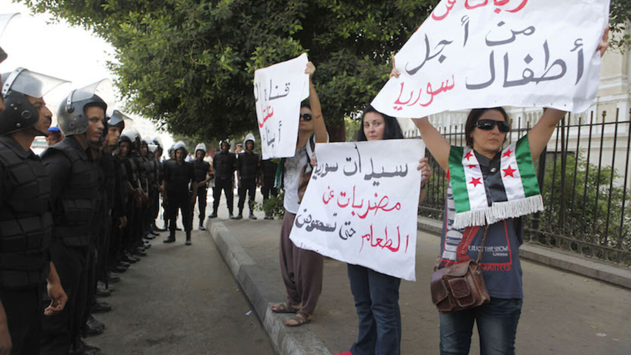 Riot police stand guard while Syrian protesters hold anti-Assad placards in front of the Arab League headquarters in Cairo where a meeting of Arab foreign ministers is taking place September 5, 2012. The placards say, "We are on hunger strike for the sake of the Syrian children". REUTERS/Asmaa Waguih (EGYPT - Tags: POLITICS CIVIL UNREST) - RTR37IEC