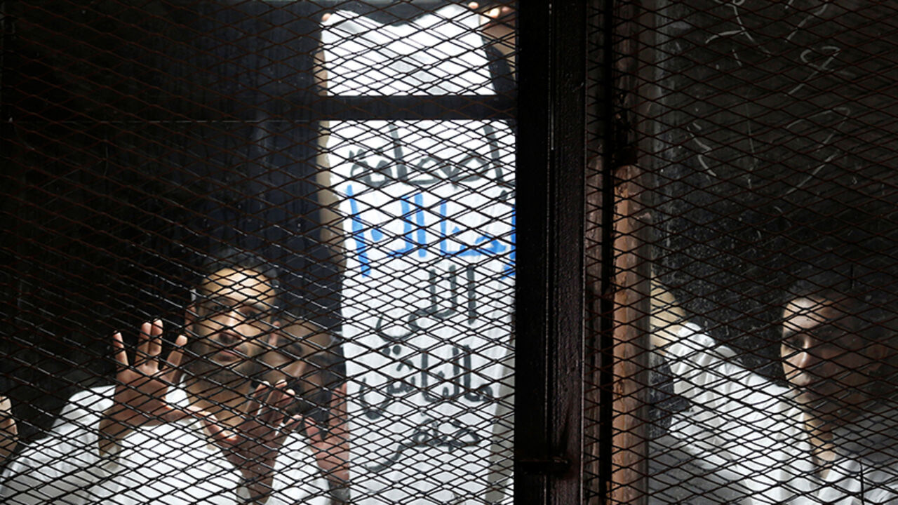 Egyptian journalists gesture behind bars during their trial at a court on the outskirts of Cairo, Egypt May 31, 2016. The banner reads, "Hey Press Syndicate, why is there no support for 10 of us?"  REUTERS/Amr Abdallah Dalsh - RTSFZK8