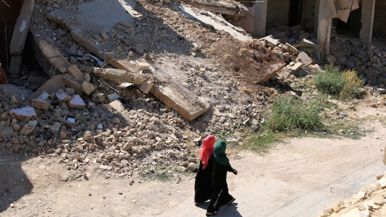 Women walk past damaged buildings along a street in the rebel-held town of Dael, in Deraa Governorate, Syria July 7, 2016. REUTERS/Alaa Al-Faqir - RTX2K6L9