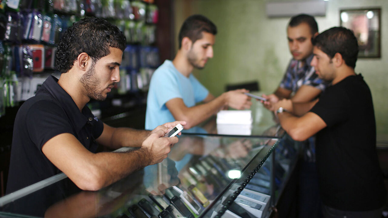 A Palestinian salesperson holds Apple's new iPhone 5 at a mobile phone store in Gaza City October 16, 2012. Apple's new iPhone 5 is selling well in the Gaza Strip despite inflated prices, reaching the Palestinian enclave via smuggling tunnels even before high-tech hub Israel next door.   REUTERS/Mohammed Salem (GAZA - Tags: POLITICS SCIENCE TECHNOLOGY BUSINESS SOCIETY TELECOMS) - RTR3970R
