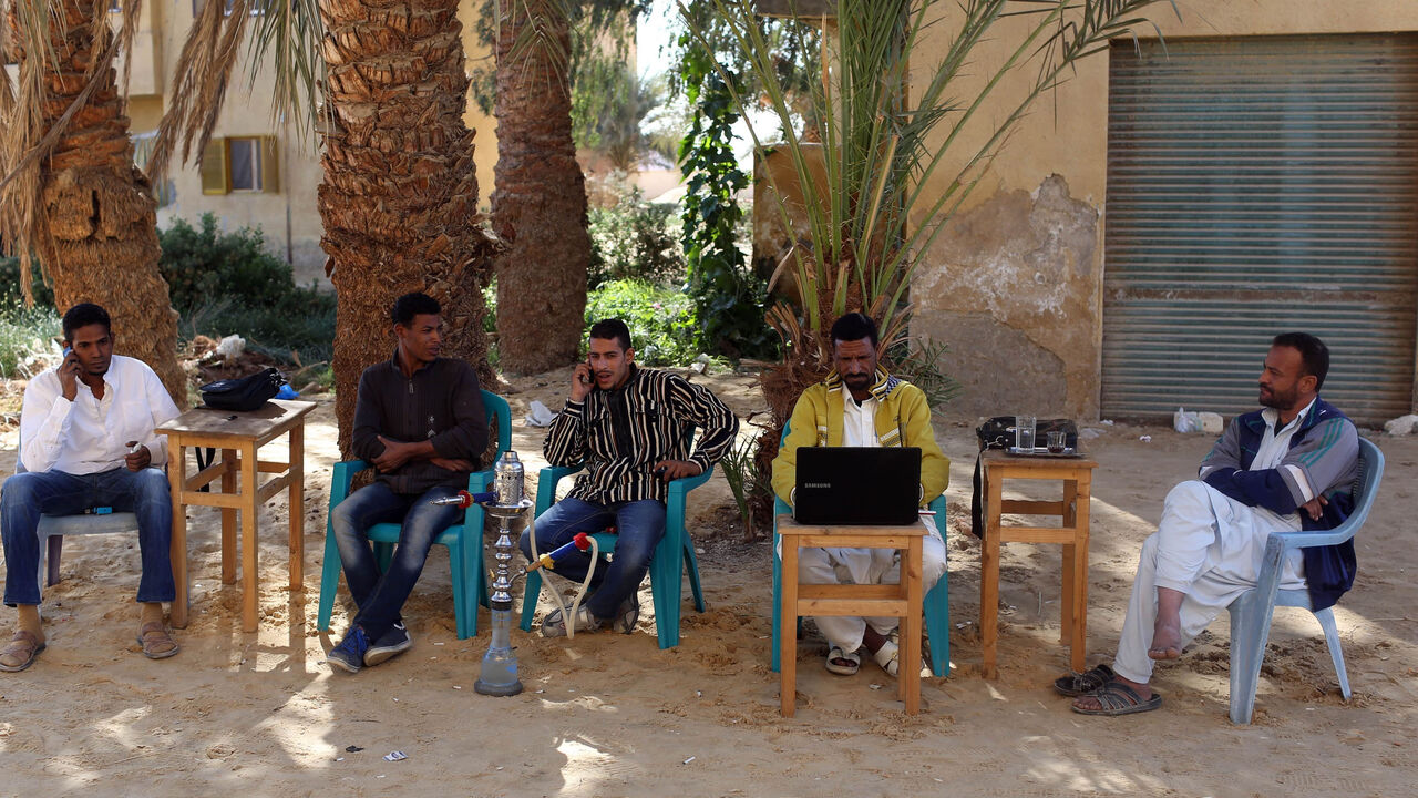 Men smoke and use their mobile phones as they sit at a small cafe in Siwa, November 22, 2014. Residents of Siwa have been hurt by declining tourism in Egypt, which received 9.5 million tourists last year, down from over 14.7 million tourists in 2010, before the uprising that ousted autocrat Hosni Mubarak. Nationwide, the situation is gradually improving and the government says tourism could recover to pre-crisis levels next year if regional turmoil spares Egypt. But Siwa, located just 50 km (30 miles) from 