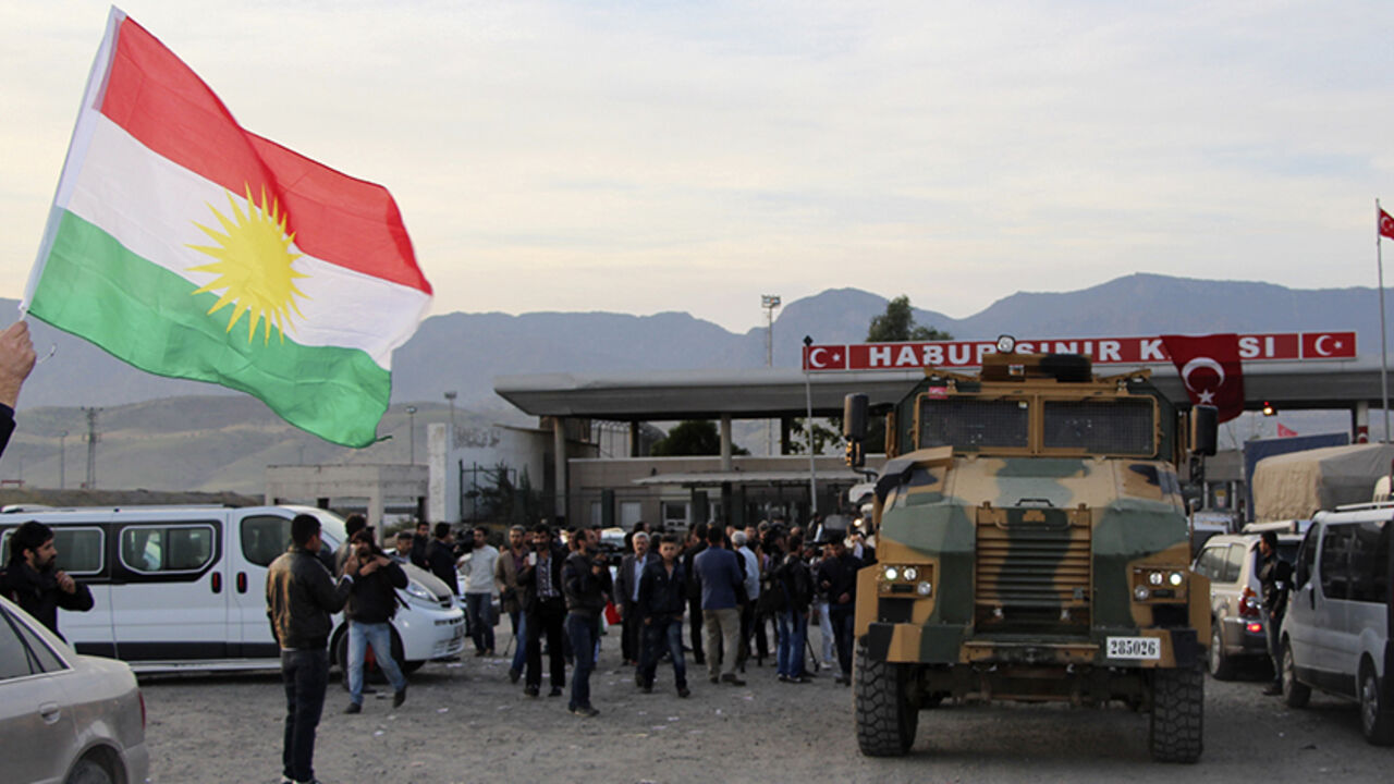 A man waves a Kurdistan flag as a Turkish military truck escorts a convoy of peshmerga vehicles at Habur border gate, which separates Turkey from Iraq, near the town of Silopi in southeastern Turkey, October 29, 2014. Iraqi peshmerga fighters arrived in southeastern Turkey early on Wednesday ahead of their planned deployment to the Syrian town of Kobani to help fellow Kurds repel an Islamic State advance, a Reuters witness said. REUTERS/Kadir Baris (TURKEY - Tags: POLITICS MILITARY CONFLICT TPX IMAGES OF TH