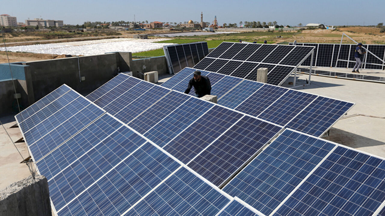 A Palestinian worker installs solar panels atop the roof of a medical centre in Gaza City March 1, 2016. REUTERS/Ibraheem Abu Mustafa - RTS9Z0H