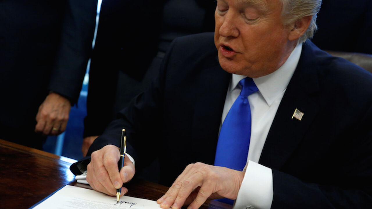 U.S. President Donald Trump signs an executive order dealing with the structure of the National Security Council, in the Oval Office at the White House in Washington, U.S. January 28, 2017. REUTERS/Jonathan Ernst - RTSXTX4