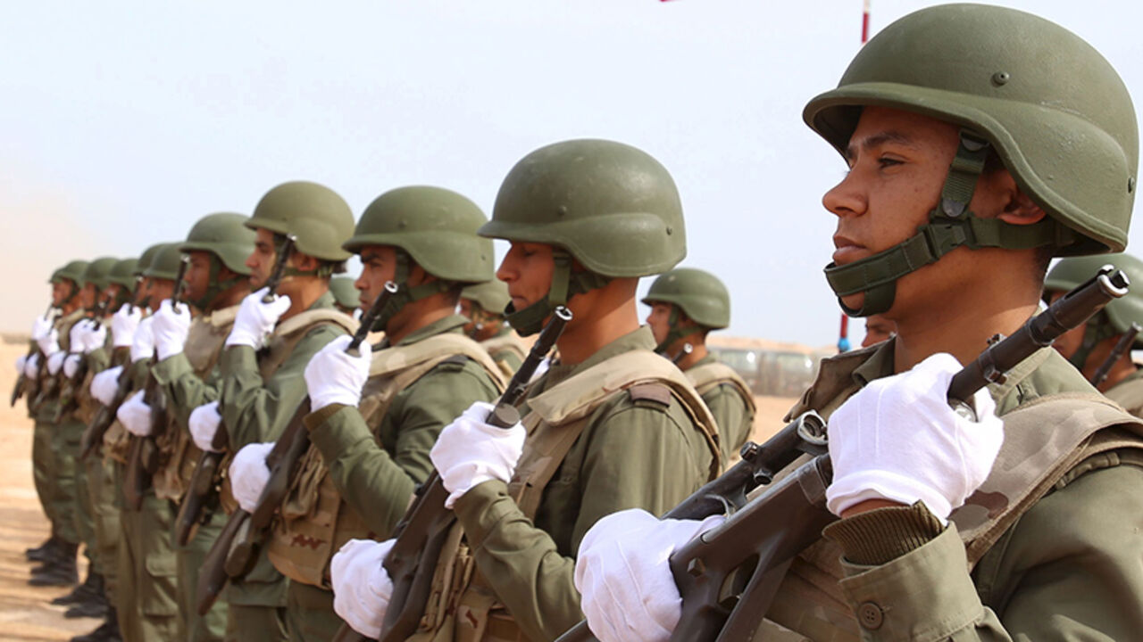 Tunisian soldiers listen to the national anthem along the frontier with Libya in Sabkeht Alyun,Tunisia February 6, 2016. Tunisia has completed a 200-km (125 mile) barrier along its frontier with Libya to try to keep out Islamist militants, and will soon install electronic monitoring systems, Defence Minister Farhat Hachani said on Saturday. REUTERS/Zoubeir Souissi - RTX25SJ3