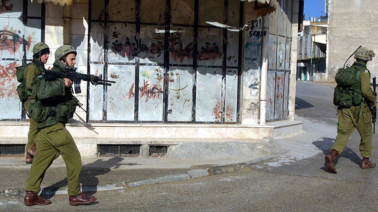 HEBRON, WEST BANK - DECEMBER 13:  Israeli soldiers patrol the desert streets December 13, 2002 in the Palestinian town of Hebron, West Bank. The Israeli Army imposed a curfew all over Hebron, after Palestinian gunmen killed two Israel Defense Forces soldiers December 12 at a roadblock near the Tomb of the Patriarchs, a Jewish and Muslim holy site in the center of the West Bank city of Hebron. The two soldiers, Maor Kalfon, 19, a male, and  Cpl. Keren Yakobi, 19, a female, were part of a Military Police unit