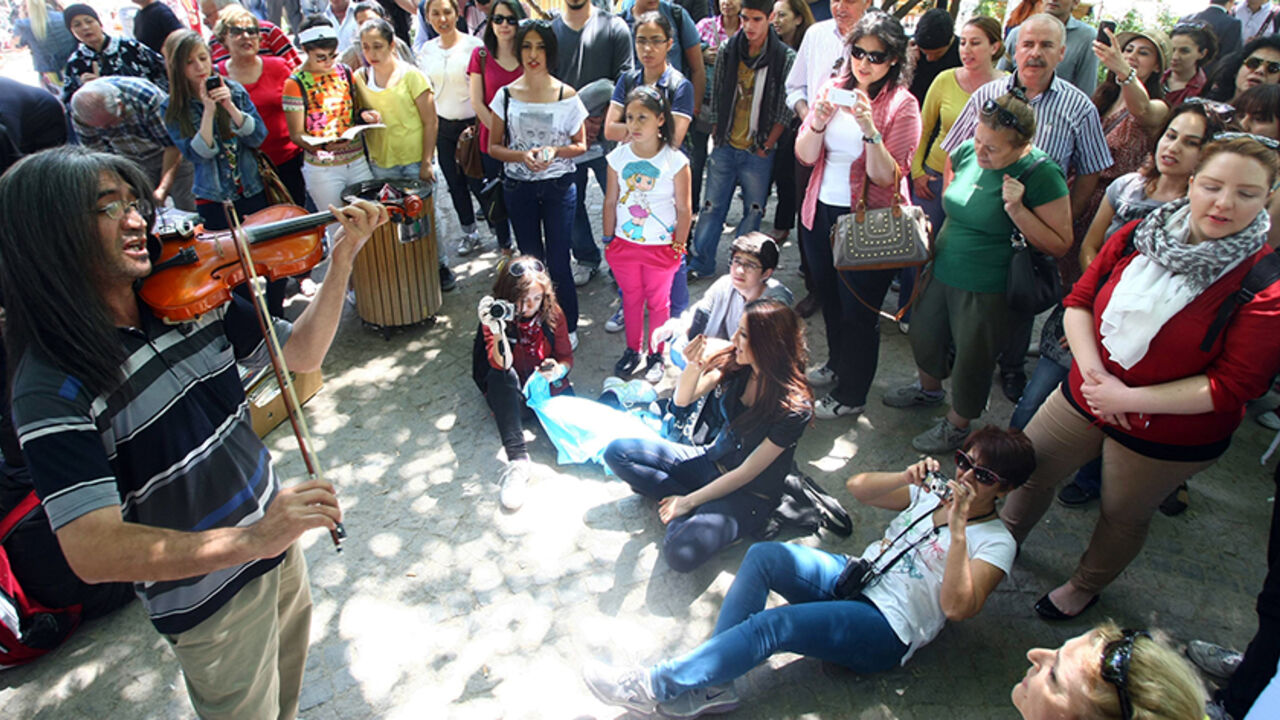 Protesters listen to a man playing the violin in a public garden in Ankara, on June 7, 2013. Turkish Prime Minister Recep Tayyip Erdogan said on June 7 his Islamic-rooted government was open to "democratic demands" and hit back at EU criticism of his handling of a week of deadly unrest. Turkey's protests began when police cracked down heavily on a peaceful campaign to save Istanbul's Gezi Park, spiralling into nationwide anti-government demos.  AFP PHOTO / ADEM ALTAN        (Photo credit should read ADEM AL
