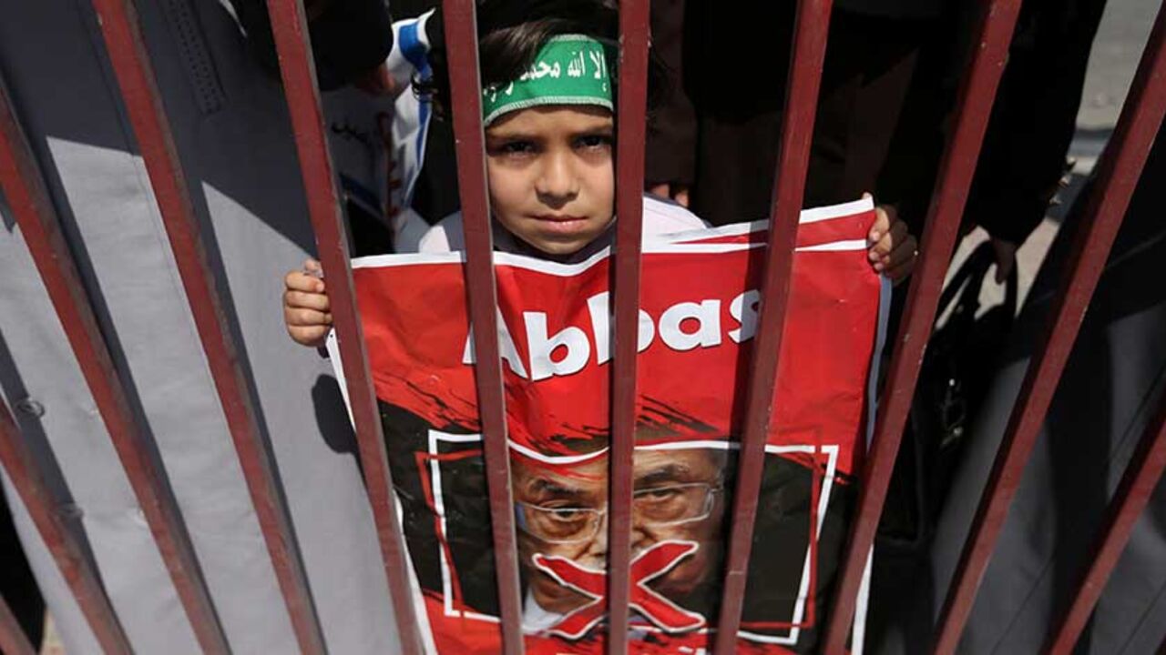 A Palestinian boy holds a crossed-out poster depicting Palestinian President Mahmoud Abbas during a protest against the blockade on Gaza, in the central Gaza Strip May 2, 2017. REUTERS/Ibraheem Abu Mustafa - RTS14RPX