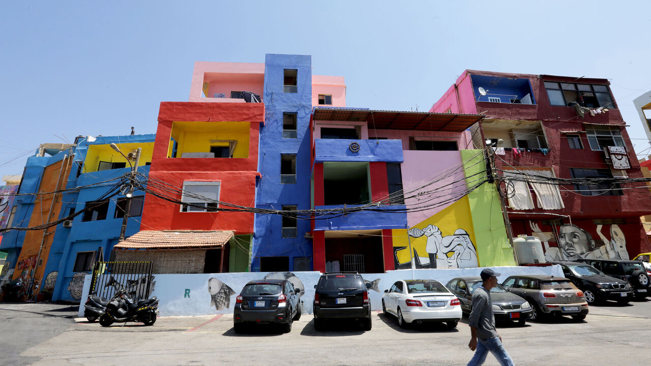 A man walks past houses, painted as part of the "Ouzville" project, in Beirut's southern Ouzai neighbourhood, on August 19, 2017.
Starting 18 months ago, Nasser began implementing a plan to invite international and local artists to beautify parts of Beirut with street art, and Ouzai in particular, by painting walls in brilliant blues, reds, yellows and greens, and adorning others with enormous murals, doodles, and cartoon characters. / AFP PHOTO / ANWAR AMRO        (Photo credit should read ANWAR AMRO/AFP/G