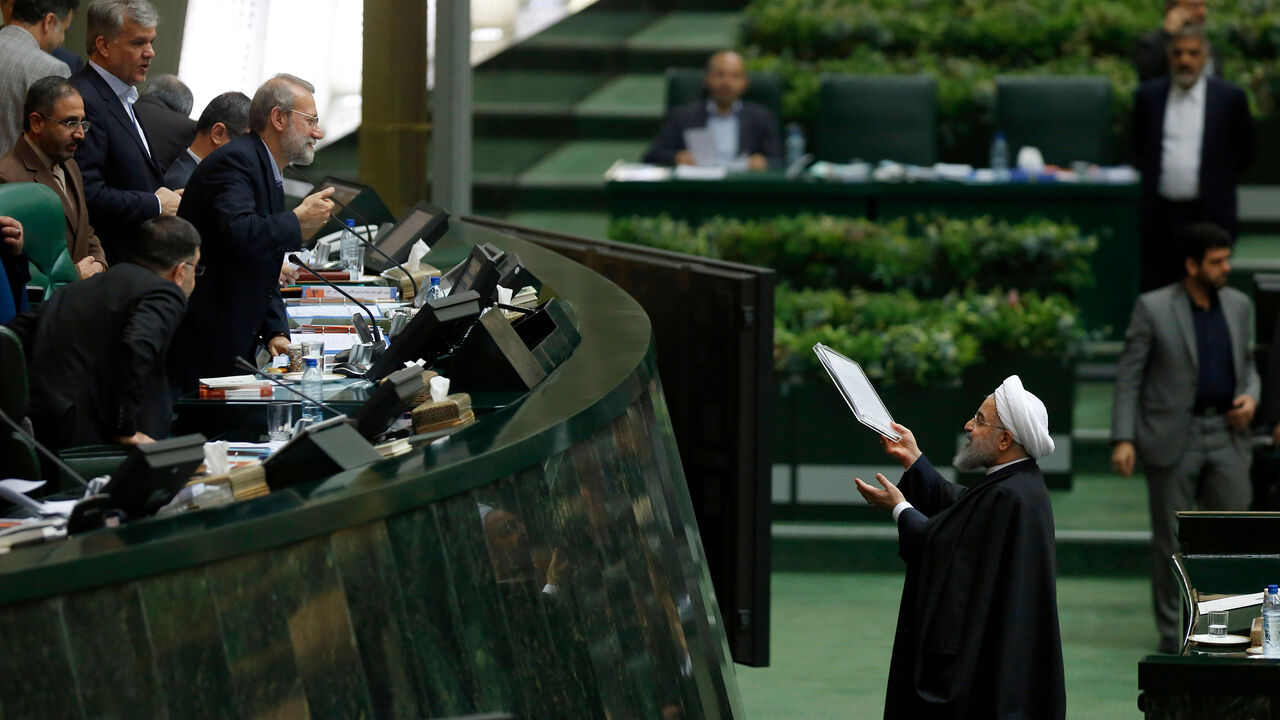 Iran's President Hassan Rouhani (R) hands out documents to Parliament Speaker Ali Larijani after presenting his budget for 2018-2019 on December 10, 2017, in Tehran. / AFP PHOTO / ATTA KENARE        (Photo credit should read ATTA KENARE/AFP/Getty Images)