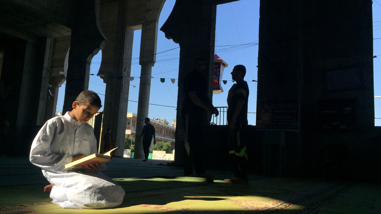 A Palestinian boy reads the Koran at a mosque in the second Friday of Muslim holy month of Ramadan, in Gaza city, June 17, 2016. REUTERS/Suhaib Salem - S1AETKLEYYAA