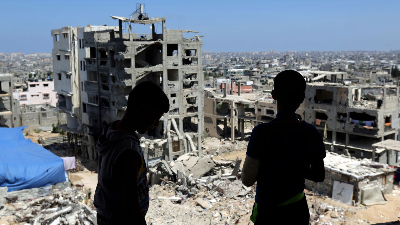 Two Palestinian teenagers look at the rubble of destroyed buildings, on June 10, 2015, which were demolished during the 50-day war between Israel and Hamas militants in the summer of 2014, in the Eastern Gaza City Shujaiya neighbourhood. AFP PHOTO / MAHMUD HAMS        (Photo credit should read MAHMUD HAMS/AFP/Getty Images)