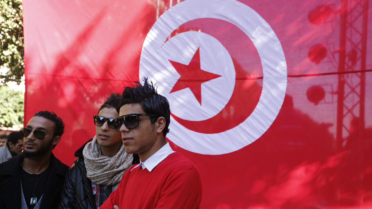 Youths pose for a photo in front a Tunisian flag during celebrations of the second anniversary of the Tunisian revolution at Avenue Habib-Bourguiba in Tunis, January 13, 2013. REUTERS/Anis Mili (TUNISIA - Tags: POLITICS CIVIL UNREST ANNIVERSARY) - GM1E91E09KE01