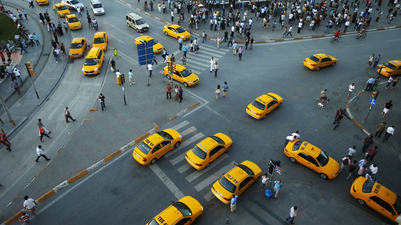 Yellow taxis pass people standing in silence during a protest at Taksim Square in Istanbul June 19, 2013. Turkey's deputy prime minister said on Wednesday he had no objection to silent anti-government protests inspired by a symbolic "Standing Man" vigil, comments that could help draw the sting out of three weeks of often violent demonstrations.  REUTERS/Marko Djurica (TURKEY  - Tags: CIVIL UNREST POLITICS TRANSPORT) - GM1E96K07FF01