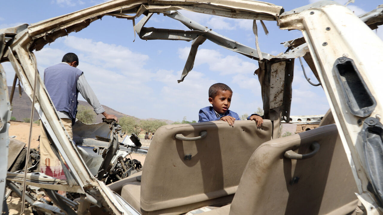 Hafidh Abdullah al-Khawlani, who survived a Saudi-led air strike stands with his father on the wreckage of a bus destroyed by the strike in Saada, Yemen September 4, 2018. His brother was killed by the air strike. Picture taken September 4, 2018. REUTERS/Naif Rahma - RC1FB49D40C0