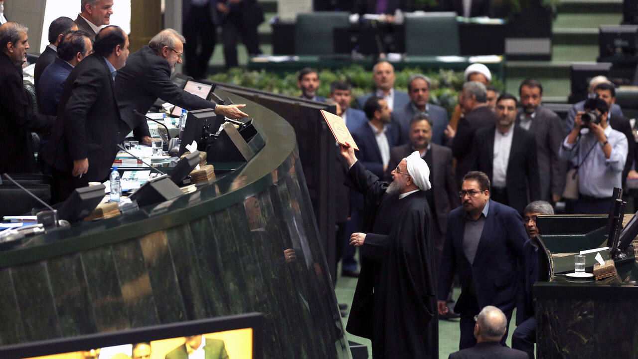 Iranian President Hassan Rouhani (C-R) submits documents outlining his budget for 2018-2019 to Parliament Speaker Ali Larijani (4th-L) in the capital Tehran on December 25, 2018. (Photo by ATTA KENARE / AFP)        (Photo credit should read ATTA KENARE/AFP/Getty Images)