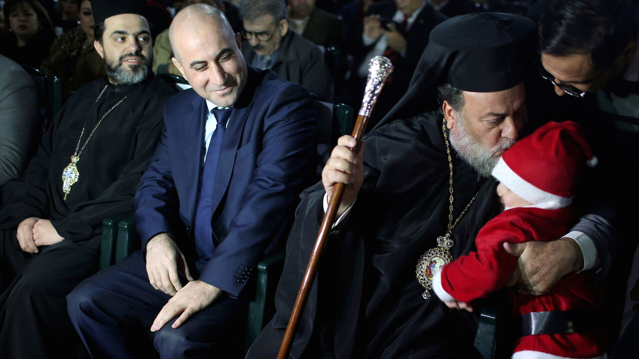 Greek Orthodox Archbishop Alexios kisses a Palestinian child dressed up as Santa Claus during a Christmas tree lighting ceremony in Gaza City December 22, 2018. Picture taken December 22, 2018. REUTERS/Ibraheem Abu Mustafa - RC15B4F1FD50