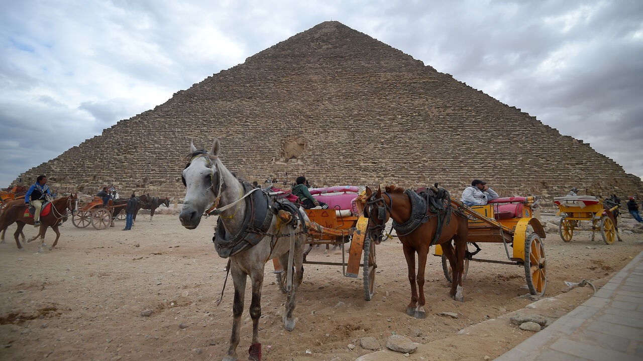 This picture taken on December 29, 2018 shows tourist horse-drawn carts waiting by the base of the Great Pyramid of Khufu (or Cheops) at the Giza necropolis on the southwestern outskirts of the Egyptian capital Cairo on December 29, 2018. (Photo by MOHAMED EL-SHAHED / AFP)        (Photo credit should read MOHAMED EL-SHAHED/AFP/Getty Images)