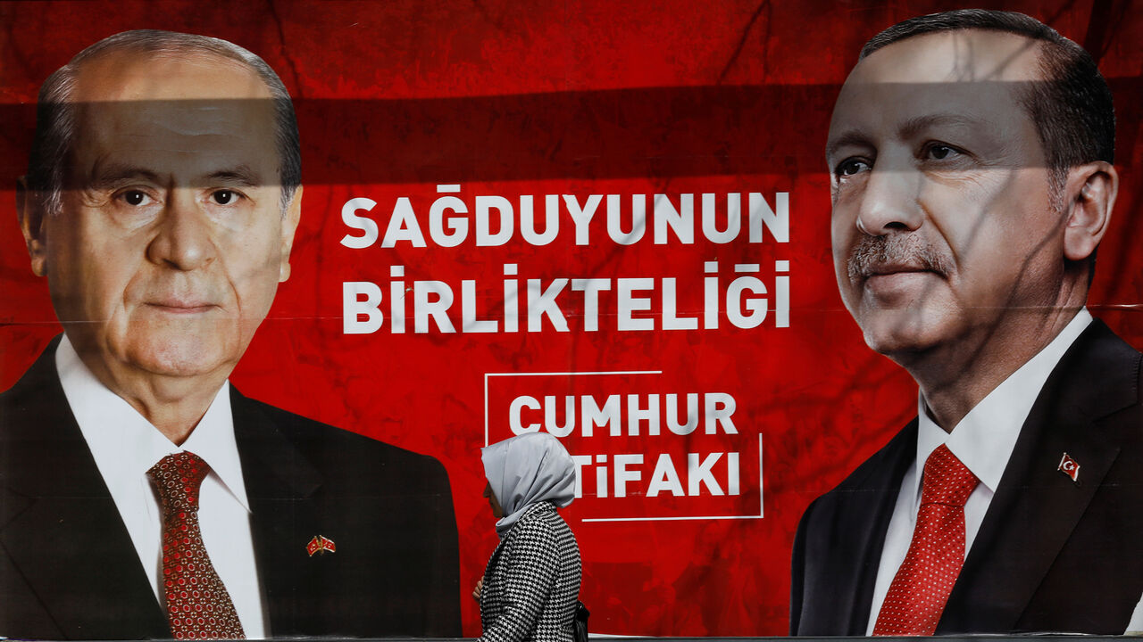 A woman walks past a banner for the upcoming local elections in Ankara, Turkey, March 27, 2019. Banner with pictures of Turkish President Tayyip Erdogan and Devlet Bahceli, leader of Nationalist Movement Party (MHP), reads: "People's Alliance: The unity of common sense." REUTERS/Umit Bektas - RC14BCF5B7C0