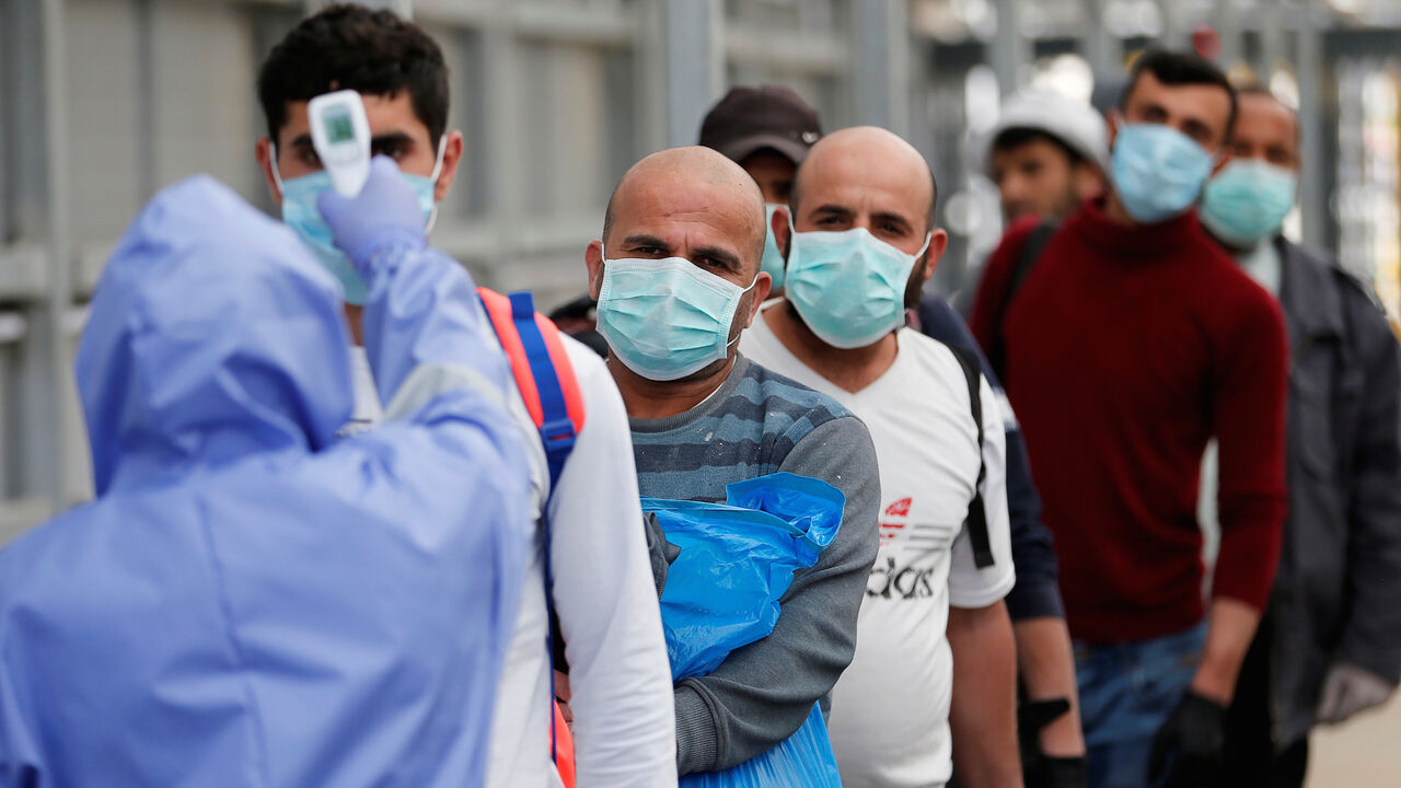A healthcare worker checks the body temperature of Palestinian workers returning from Israel, amid concerns over the spread of the coronavirus disease (COVID-19), outside the Israeli-controlled Meitar checkpoint, near Hebron in the Israeli-occupied West Bank April 7, 2020. Picture taken April 7, 2020. REUTERS/Mussa Qawasma - RC280G9AG6MG