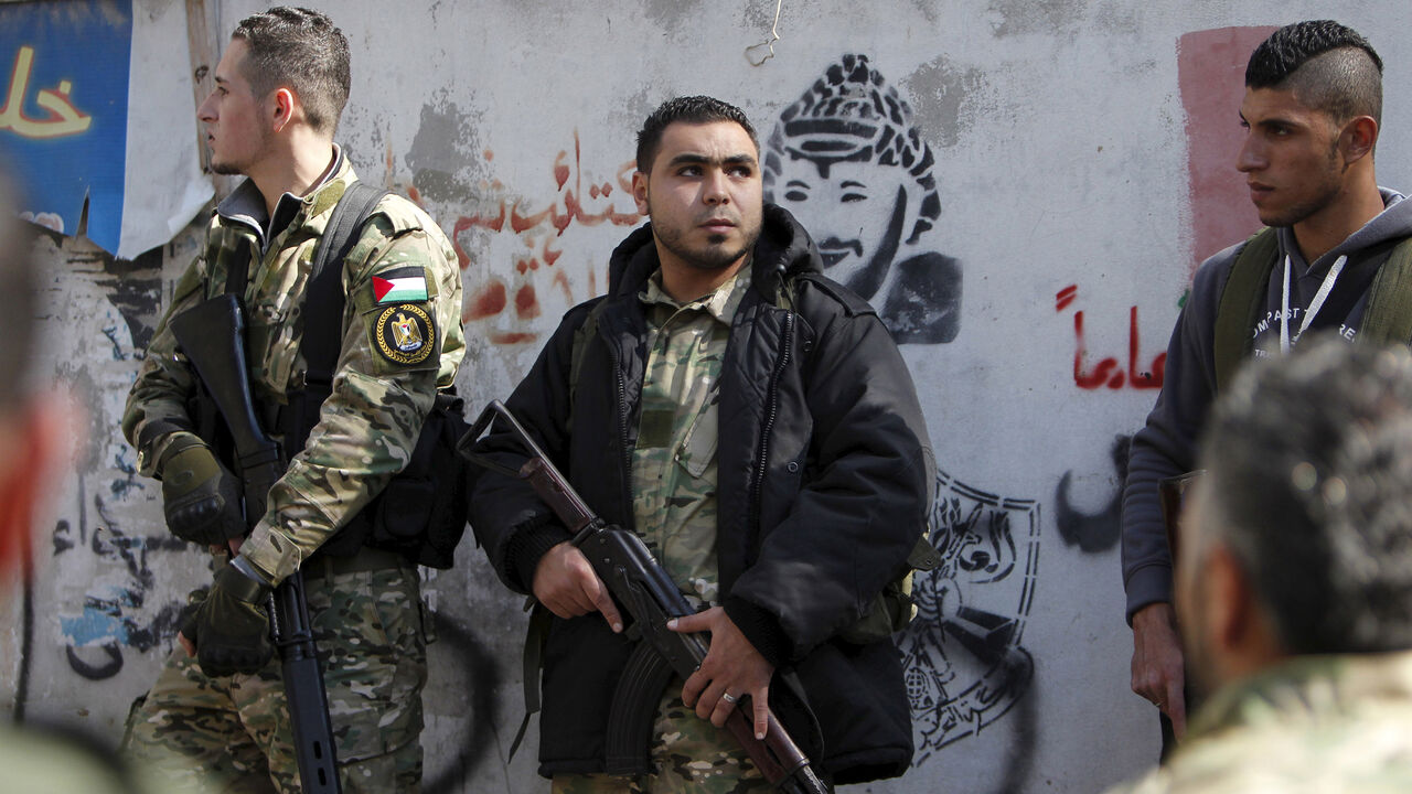 Armed gunmen attend the funeral of Fathi Zaydan, a Fatah official responsible for the Palestinian camp of Mieh Mieh, after an explosion that killed him yesterday, during his funeral in Mieh Mieh Palestinian refugee camp, near the port-city of Sidon, Lebanon, April 13, 2016. The wall shows a graffiti of late Palestinian leader Yasser Arafat. REUTERS/Ali Hashisho - GF10000381452