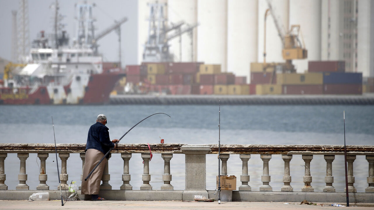 TOPSHOT - A Libyan man fishes on the seaside promenade opposite Tripoli's main port on April 22, 2019. - Despite the war on Tripoli's doorstep, residents are filling the salons and cafes in some quarters of the Libyan capital as they carry on with life as best they can. Tension has been high in Tripoli since military chief Khalifa Haftar launched an offensive on April 4, aimed at seizing the capital from the UN-backed unity government based there. (Photo by Mahmud TURKIA / AFP)        (Photo credit should r