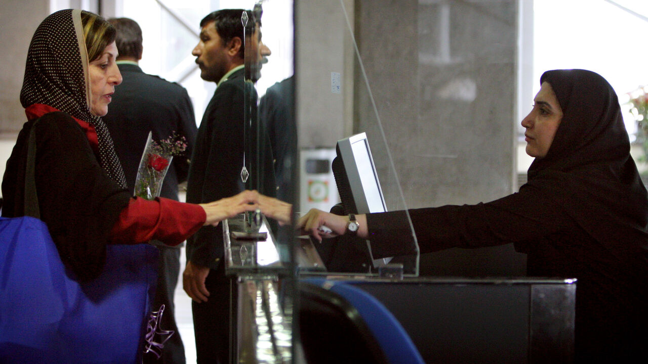 An Iranian police woman checks a passport at the Imam Khomeini International Airport 45 km (27.96 miles) south of Tehran April 30, 2005. Iran opened its new main international airport on Saturday, despite warnings from at least two countries that the runway may be unsafe. The Imam Khomeini International Airport, built to serve the capital Tehran, received a first commercial flight from Dubai almost exactly a year after its inauguration was aborted when the military closed it down because of concern over sec
