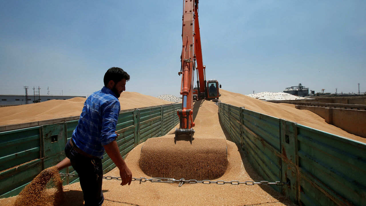 A farmer helps an excavator to unload wheat grain at a silo in Mosul, Iraq June 12, 2019. Picture taken June 12, 2019. REUTERS/Azad Lashkari - RC15C546A580