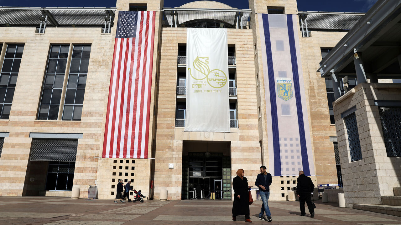 People walk at the Jerusalem's city hall as the American and Israeli national flags hang on the municipality building in Jerusalem December 7, 2017. REUTERS/Ammar Awad - RC121A0E97D0