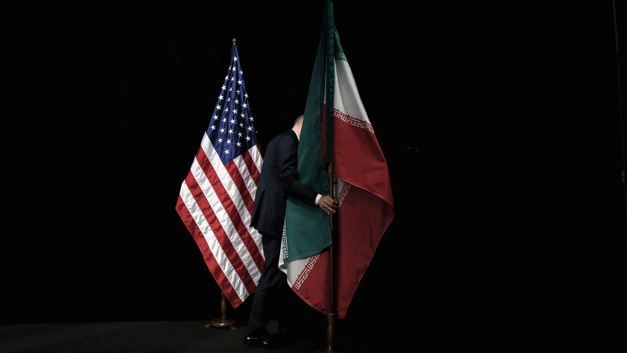 A staff member removes the Iranian flag from the stage after a group picture with foreign ministers and representatives of the U.S., Iran, China, Russia, Britain, Germany, France and the European Union during the Iran nuclear talks at the Vienna International Center in Vienna, Austria July 14, 2015. To match Analysis USA-ELECTION/IRAN      REUTERS/Carlos Barria/File Photo - S1AEULVWKDAA