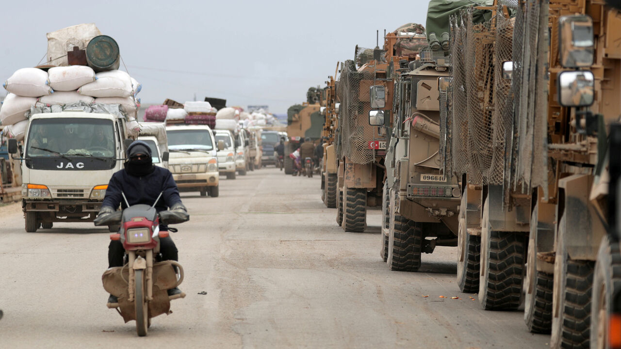 A man rides on a motorbike past Turkish military vehicles in Hazano near Idlib, Syria, February 11, 2020. REUTERS/Khalil Ashawi - RC2HYE9DX8HU
